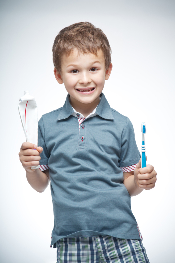 A kid holding dental cleaning accessories to show that pediatric dental care is important and cn be done at home.