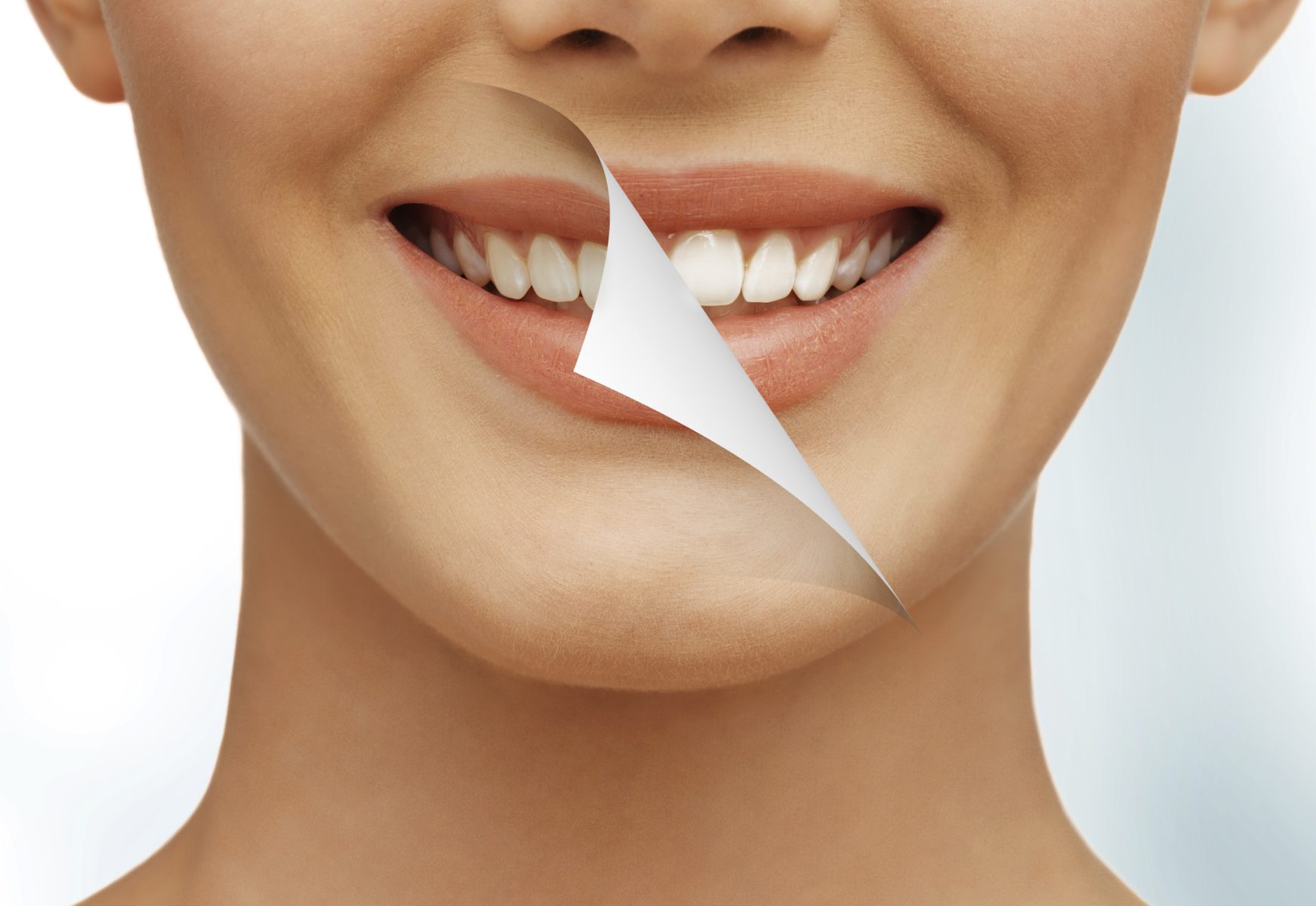 A woman smiling with the page turning to reveal whiter teeth as a result of tooth whitening treatments