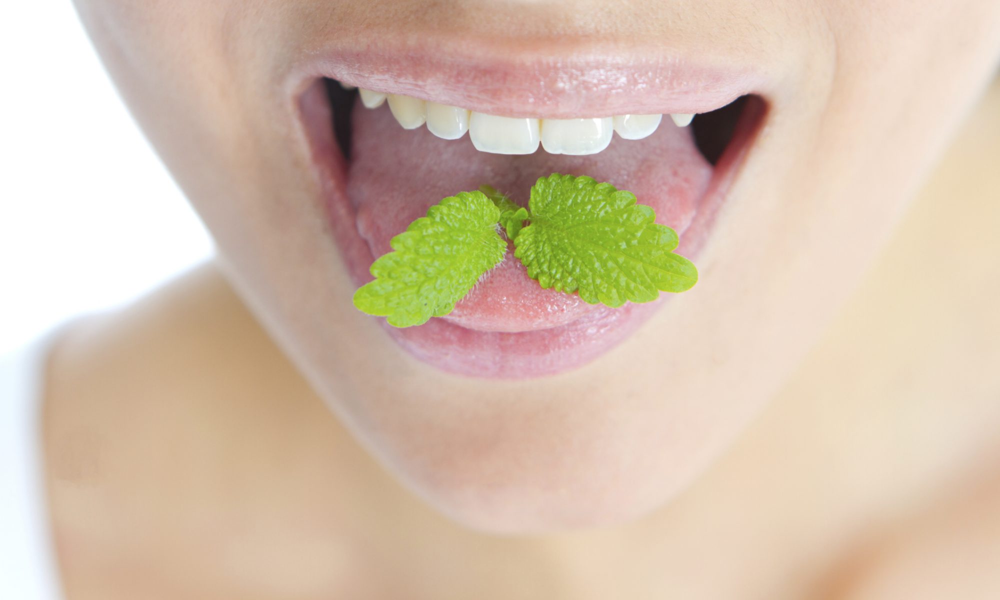 A woman with mint on her tongue as a visual way to represent clean teeth and fresh breath