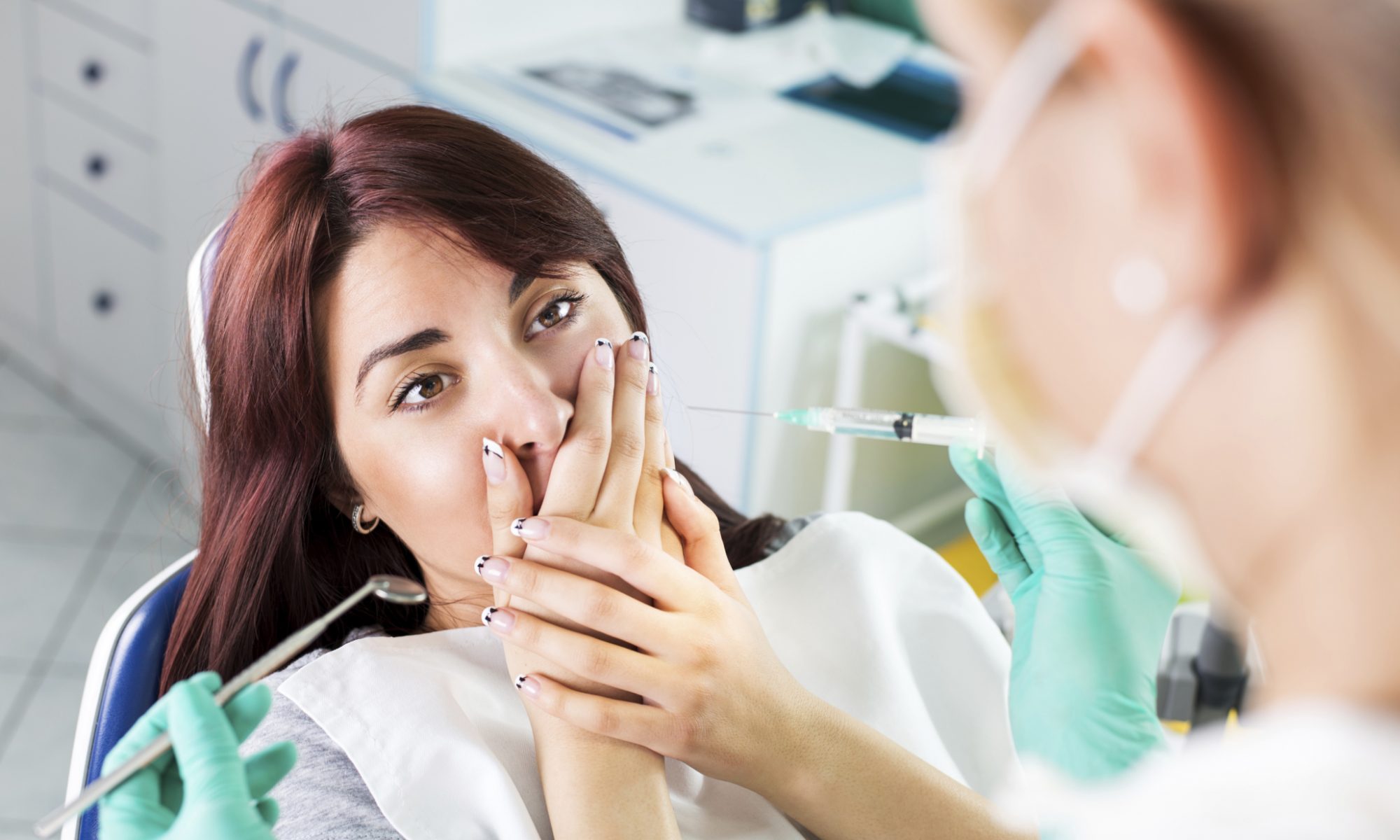 Woman at the dentist shielding her mouth because she is scared or has dental anxiety